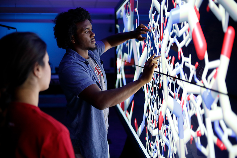 Two people interacting with the IQ Wall.