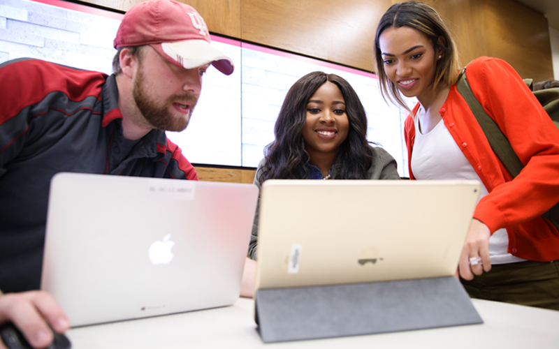 Support Center staff member helping two students on laptops