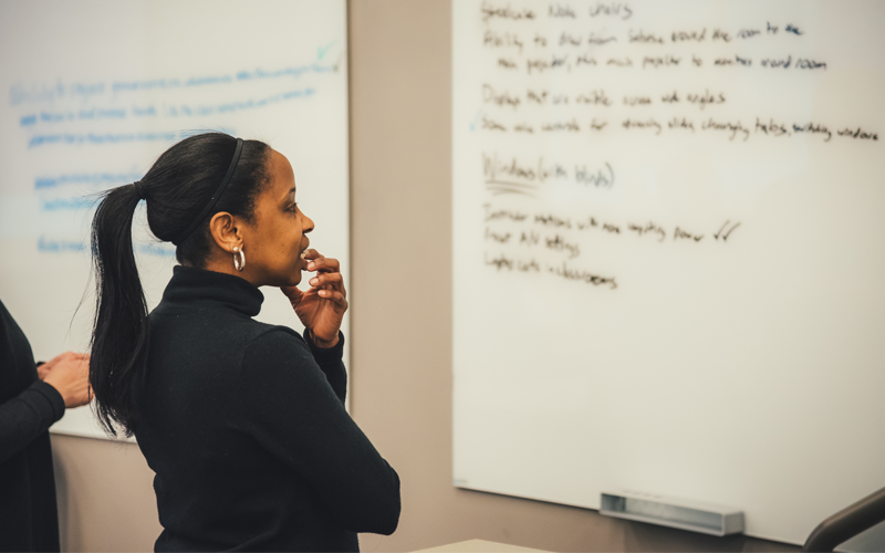 A Mosaic Faculty Fellow contemplating information on classroom whiteboard