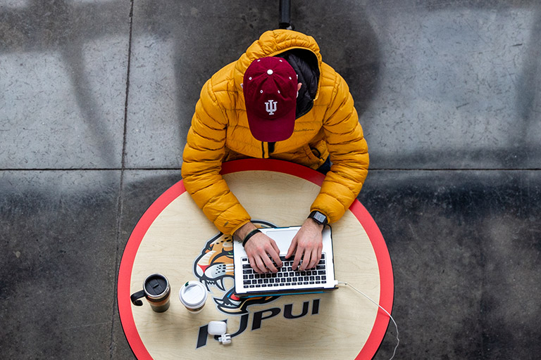 Person sits at table working on a laptop.