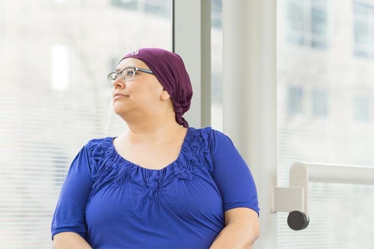 Image of a breast cancer patient look out a window to the left