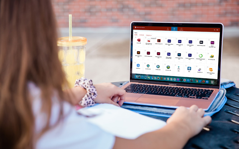 A student sitting outdoors on their laptop with IUanyWare on the screen.